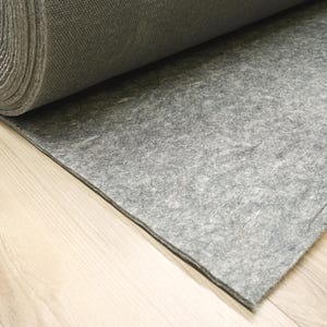 May include: A roll of gray felt fabric partially unrolled, revealing the textured surface. The felt is a solid, neutral color, suitable for various craft and design projects. The fabric rests on a light-colored wooden surface.