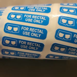 Puede incluir: Un rollo de pegatinas azules y blancas con el texto "FOR RECTAL USE ONLY" y un gráfico de un par de ropa interior.