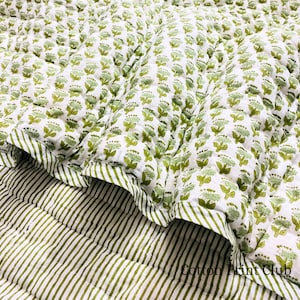 May include: A white and green floral patterned quilt with a striped border. The quilt features a repeating pattern of green floral designs on a white background. The border has green and white stripes. The text "Cotton Print Club" is visible.