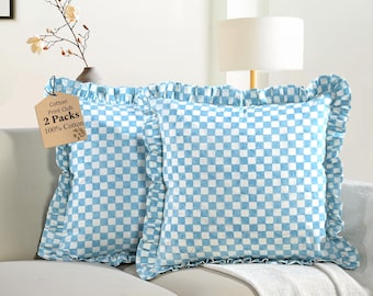 May include: Two square throw pillows with a light blue and white checkered pattern. The pillows have ruffled edges and are labeled "Cotton Print Club, 2 Packs, 100% Cotton". They are placed on a white sofa.