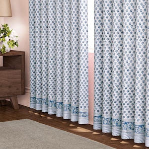 Peut inclure: Rideaux à motifs floraux blancs et bleus. Les rideaux présentent un motif répétitif de petites fleurs bleues sur fond blanc. La bordure inférieure présente un motif floral bleu détaillé. Les rideaux sont suspendus devant une fenêtre.