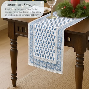 Luxurious Apatite blue table runner with intricate floral patterns inspired by India’s ancient forts, displayed on a dark wooden table. Text overlay highlights the design's roots in tradition and timeless artistry, suggesting elegance and cultural richness. A wine glass and festive greenery add a sophisticated touch to the scene.