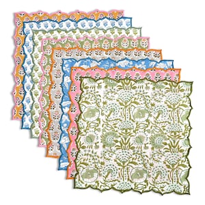 Puede incluir: Una pila de servilletas de tela estampadas y coloridas con bordes festoneados. Las servilletas presentan diseños florales en varios colores, incluyendo verde, rosa, azul, naranja y amarillo. Las servilletas están apiladas en ángulo, mostrando los diferentes patrones.