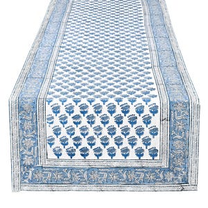 Reversible apatite blue hand‑block printed cotton table runner, featuring floral motifs and decorative borders in shades of blue over a creamy white background; boho‑style Indian linen ideal as a washable centerpiece piece for dining tables, weddings, or farmhouse home décor.