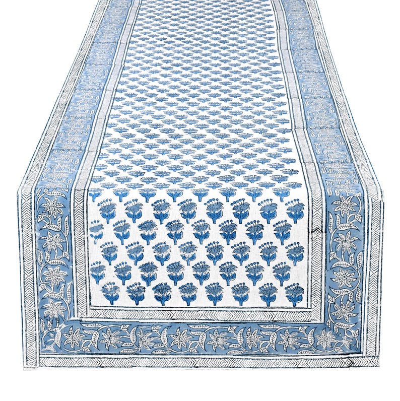 Reversible apatite blue hand‑block printed cotton table runner, featuring floral motifs and decorative borders in shades of blue over a creamy white background; boho‑style Indian linen ideal as a washable centerpiece piece for dining tables, weddings, or farmhouse home décor.