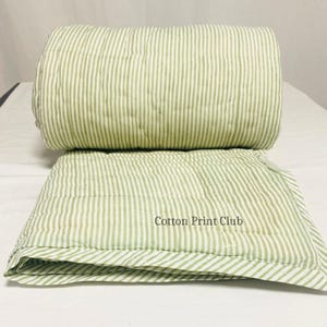 Lifestyle shot of reversible cotton Kantha quilt with stripe pattern, adding eco-friendly, artisanal charm to a cozy bedroom setup, great as throw, coverlet, or decorative bedding. Artisan-crafted green stripe quilt, fully reversible, showing hand block printed stripes on cotton, soft and durable, perfect for everyday use or gifting, farmhouse and boho décor compatible.