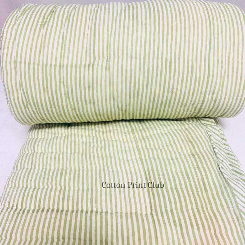 King-size Kantha bedspread with green stripes, reversible cotton quilt, showcasing lightweight comfort, timeless boho design, perfect for layering, bedroom décor, or home photography. Close-up of fabric edges and stitching, hand block printed green stripes on both sides, durable cotton quilt, adding authentic artisanal charm to boho, farmhouse, and modern interiors.