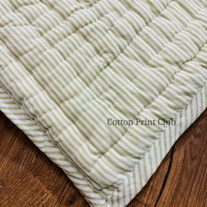 Green stripe cotton quilt draped over sofa or bed, reversible design, soft breathable cotton, handcrafted kantha stitching, perfect for boho, farmhouse, or Indian-inspired décor accents. Flat-lay image of reversible green stripe Kantha quilt, highlighting 100% cotton fabric, hand block printed stripes, lightweight yet cozy, ideal for King or Queen bedspread, throw, or décor gift.