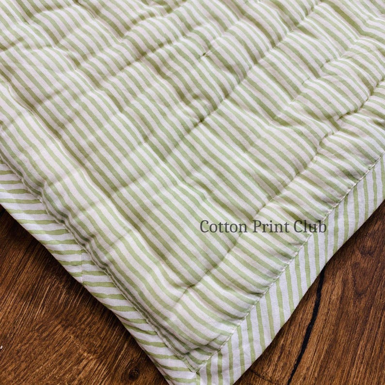 Green stripe cotton quilt draped over sofa or bed, reversible design, soft breathable cotton, handcrafted kantha stitching, perfect for boho, farmhouse, or Indian-inspired décor accents. Flat-lay image of reversible green stripe Kantha quilt, highlighting 100% cotton fabric, hand block printed stripes, lightweight yet cozy, ideal for King or Queen bedspread, throw, or décor gift.
