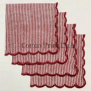 Könnte beinhalten: Set aus drei rot-weiß gestreiften Servietten mit gewellten Kanten. Die Servietten haben ein vertikales Streifenmuster und einen dekorativen roten Rand. Der Text "Cotton Print Club" ist auf den Servietten zu sehen.