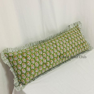 Puede incluir: Un cojín rectangular verde con un estampado floral en amarillo y blanco. El cojín tiene un borde con volantes con un patrón de rayas. El texto "Cotton Print Club" es visible en el cojín.