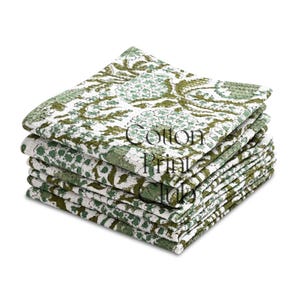 May include: A stack of cotton napkins with a white and green floral print. The napkins have a textured appearance and the words "Cotton Print Hub" are printed on the top napkin.
