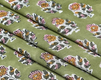 May include: Green fabric with a repeating floral pattern. The flowers are pink, white, and yellow with green leaves.