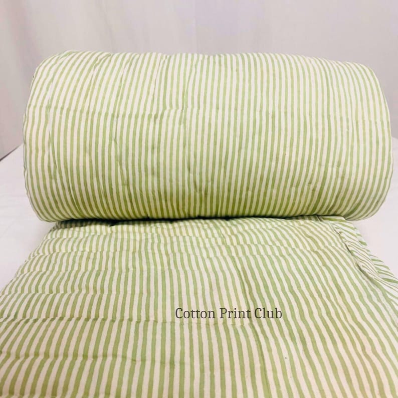 King-size green stripe cotton quilt displayed on a bed, lightweight and breathable, ideal for layering or as a standalone bedspread, blending farmhouse, boho, and minimalist décor styles. Soft cotton Kantha quilt with striped pattern, fully reversible, perfect for cozy bedroom comfort, sustainable and handmade, adding timeless elegance to any King or Queen bed.