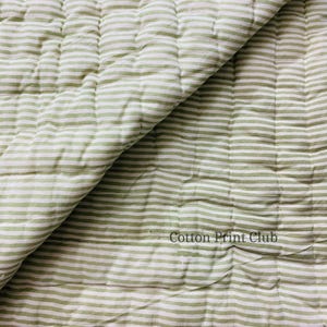 Close-up of fabric edges and stitching, hand block printed green stripes on both sides, durable cotton quilt, adding authentic artisanal charm to boho, farmhouse, and modern interiors. Green stripe cotton quilt draped over sofa or bed, reversible design, soft breathable cotton, handcrafted kantha stitching, perfect for boho, farmhouse, or Indian-inspired décor accents.
