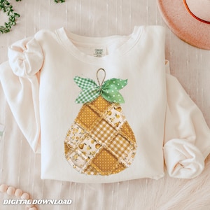 May include: Cream-colored sweatshirt featuring a patchwork pear design with yellow and white floral and gingham patterns. The pear has a green gingham bow and a string loop. The text "DIGITAL DOWNLOAD" is at the bottom.