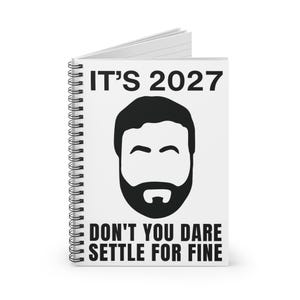 May include: A white spiral-bound notebook featuring a black graphic of a bearded face in the center. The text IT'S 2027 is printed in black at the top, and the text DON'T YOU DARE SETTLE FOR FINE is printed in black at the bottom of the cover.