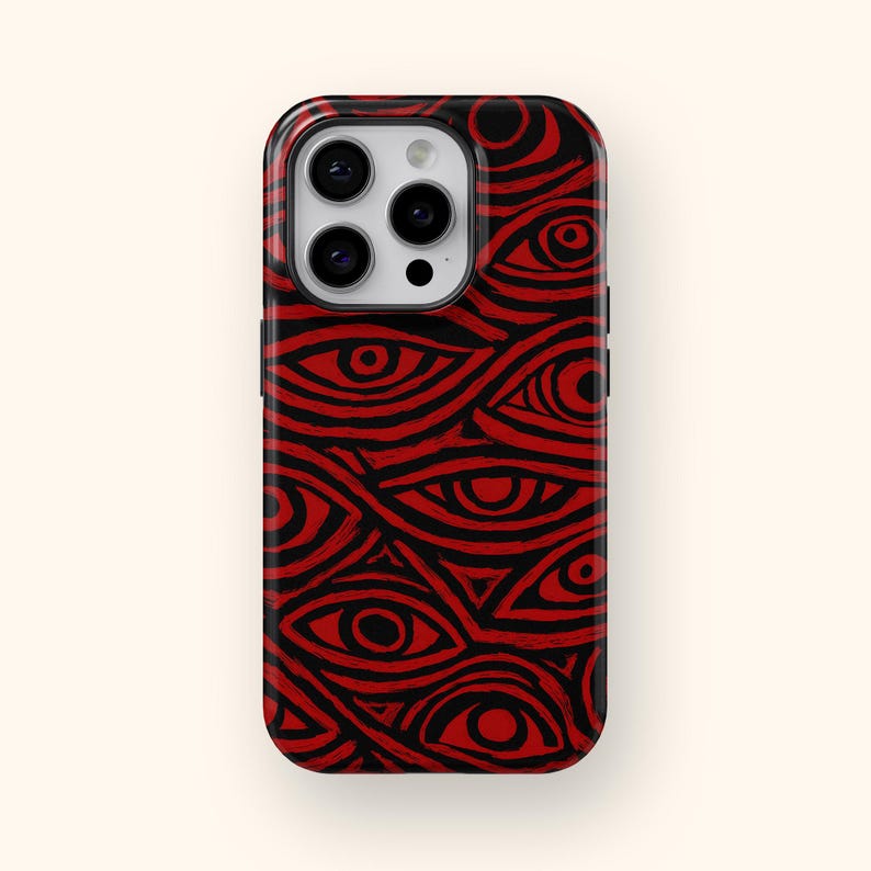 Puede incluir: Una funda de tel&eacute;fono con un patr&oacute;n repetido de ojos rojos sobre un fondo negro. La funda tiene un acabado brillante y un recorte para la c&aacute;mara. El dise&ntilde;o es un gr&aacute;fico audaz e impactante.