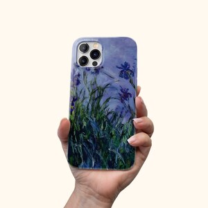 Może przedstawiać: Przezroczyste etui na telefon z obrazem fioletowych irys&oacute;w i zielonych liści na niebieskim tle. Etui ma wycięcie na aparat telefonu.