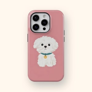 K&ouml;nnte beinhalten: Rosafarbene Handyh&uuml;lle mit einer Cartoon-Illustration eines wei&szlig;en Hundes mit blauem Halsband und goldenem Anh&auml;nger. Die Handyh&uuml;lle hat ein schwarzes Kameramodul und schwarze Seitentasten. Der Hund ist mittig platziert.