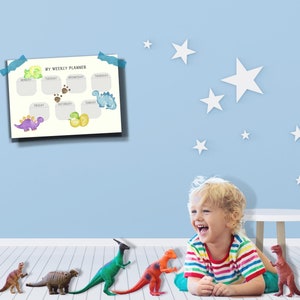 May include: A child plays with dinosaur toys in a room with a blue wall and white stars. A weekly planner with a dinosaur theme is on the wall. The planner has the days of the week listed and space for writing.