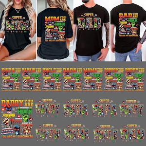 Op de afbeelding: Zwarte T-shirts met superheldenontwerpen. Eén shirt zegt "SUPER MOM" en een ander "SUPER DAD". Andere shirts zeggen "PAPA", "UNCLE", "DADA", "MAMA", "POPPY", "DADDY", "FAMILY", "GRANDPA", "UNCLE" en "MIKE".