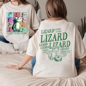 May include: Cream-colored t-shirt featuring a cartoon lizard design. The front displays a grid of colorful lizards and the text "LIZARD LIZARD LIZARD". The back has a large green "LIZARD" graphic and a lizard illustration.