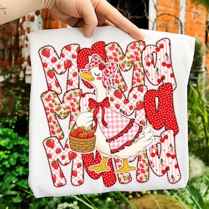 May include: White t-shirt with a whimsical design featuring the word "MAMA" in a strawberry-themed font. A cartoon goose wearing a gingham apron and holding a basket of strawberries is in the center. The design is in red, pink, and white.