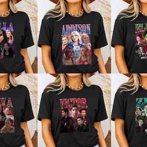 May include: Black short-sleeved t-shirts featuring various character designs with names like "Willa," "Addison," "Eliza," "Nova," "Victor," and "Zed." Each design includes a group of people in a vintage style.
