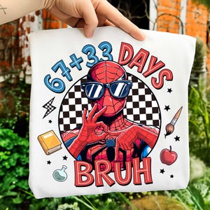 May include: White tote bag featuring a graphic of Spider-Man wearing sunglasses, with the text "67+33 DAYS BRUH." The design includes a checkered background, a lightning bolt, a book, a paintbrush, an apple, and stars.
