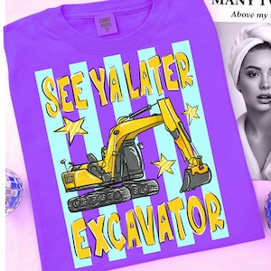 Op de afbeelding: Paarse t-shirt met een afbeelding van een gele graafmachine en de tekst "SEE YA LATER EXCAVATOR" in geel. Het ontwerp bevat blauwe verticale strepen en gele sterren. Het shirt heeft een ronde hals en korte mouwen.