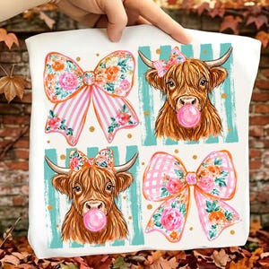 Può includere: Una borsa tote bianca con un design a griglia ripetuto che presenta due illustrazioni di mucche Highland marroni con fiocchi floreali e bolle di gomma da masticare rosa, alternate a due grandi fiocchi decorativi con strisce rosa e motivi floreali.