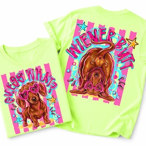 Op de afbeelding: Twee neon groene t-shirts met teckelafbeeldingen. Eén shirt zegt "Guess Whats" met een hond met een hartvormige bril. De andere zegt "Wiener Butt" met de achterkant van een hond. Beide shirts hebben roze en blauwe accenten.