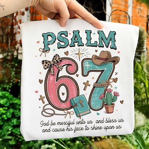 Könnte beinhalten: Weiße Tragetasche mit dem Text "PSALM 67" in Türkis und Rosa, mit Cowboyhut, Kaktus und Bibel. Die Tasche enthält auch das Zitat "Gott sei uns gnädig und segne uns und lasse sein Angesicht leuchten über uns."