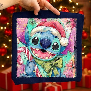 Puede incluir: Un cojín cuadrado azul marino con un personaje de dibujos animados, Stitch, con un gorro de Papá Noel y un bastón de caramelo. El fondo tiene un diseño festivo y colorido con copos de nieve y un lazo verde.