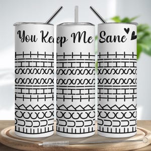 Könnte beinhalten: Drei weiße Edelstahlbecher mit schwarzem Text "You Keep Me Sane" und einem Herzsymbol. Die Becher haben schwarze geometrische Muster und werden mit Strohhalmen und einer Reinigungsbürste geliefert.