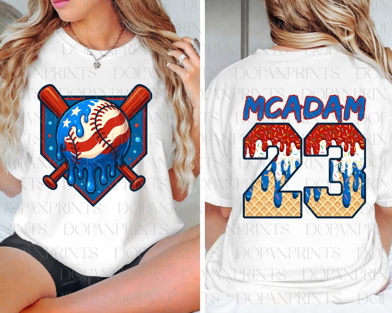 May include: White t-shirt featuring a baseball design with a patriotic theme. The front graphic includes a baseball with red and white stripes and blue stars, with crossed bats. The back displays the name "MCADAM" and the number "23".