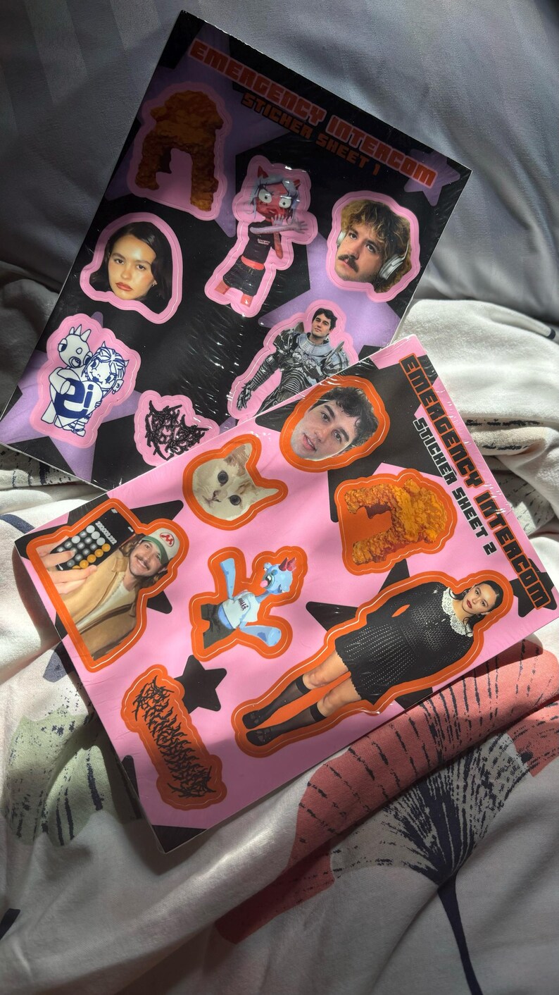 May include: Two sticker sheets with various images, including portraits, cartoon characters, and abstract shapes. The sheets are labeled "Emergency Intercom Sticker Sheet 1" and "Emergency Intercom Sticker Sheet 2". The stickers have a pink and black color scheme.