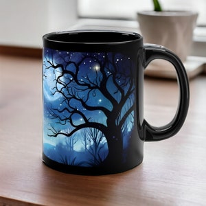 May include: Black ceramic mug with a heat-sensitive design. The design features a silhouette of a tree with branches reaching up to a crescent moon and stars against a blue night sky.