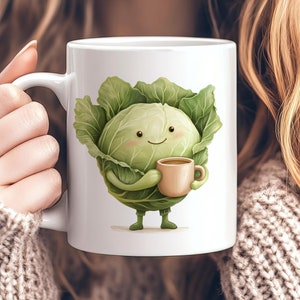 May include: White ceramic mug with a cartoon illustration of a green cabbage holding a brown mug. The cabbage has a smiling face and is wearing a green stem.