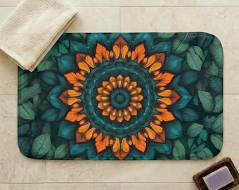 May include: A rectangular bath mat with a mandala design in shades of orange, teal, and green. The mat is surrounded by green leaves. A beige towel and a wooden soap dish with a bar of soap are also present.