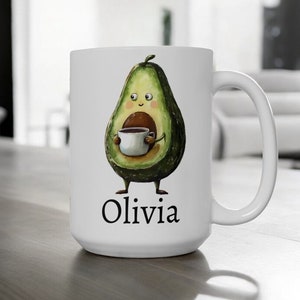 May include: White ceramic coffee mug with a cartoon avocado holding a cup of coffee. The avocado has a smiling face and the text "Olivia" is printed below the avocado.