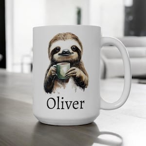 Könnte beinhalten: Weiße Keramiktasse mit einer Aquarell-Illustration eines Faultiers, das eine Tasse Kaffee hält. Die Tasse trägt den Namen "Oliver" auf der Unterseite.