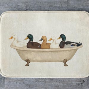 Puede incluir: Alfombra de baño rectangular crema con una ilustración de acuarela de cinco patos en una bañera vintage. Los patos son de varios colores, incluyendo blanco, marrón y verde, y la bañera tiene patas de garra.