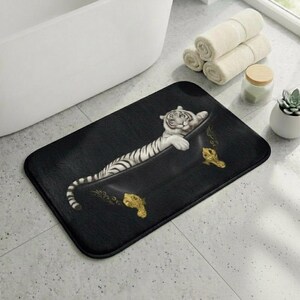 May include: Black rectangular bath mat featuring a white tiger relaxing in a black bathtub. The tiger has black stripes and is lying down. The bathtub has gold accents. The mat is on a tiled floor.