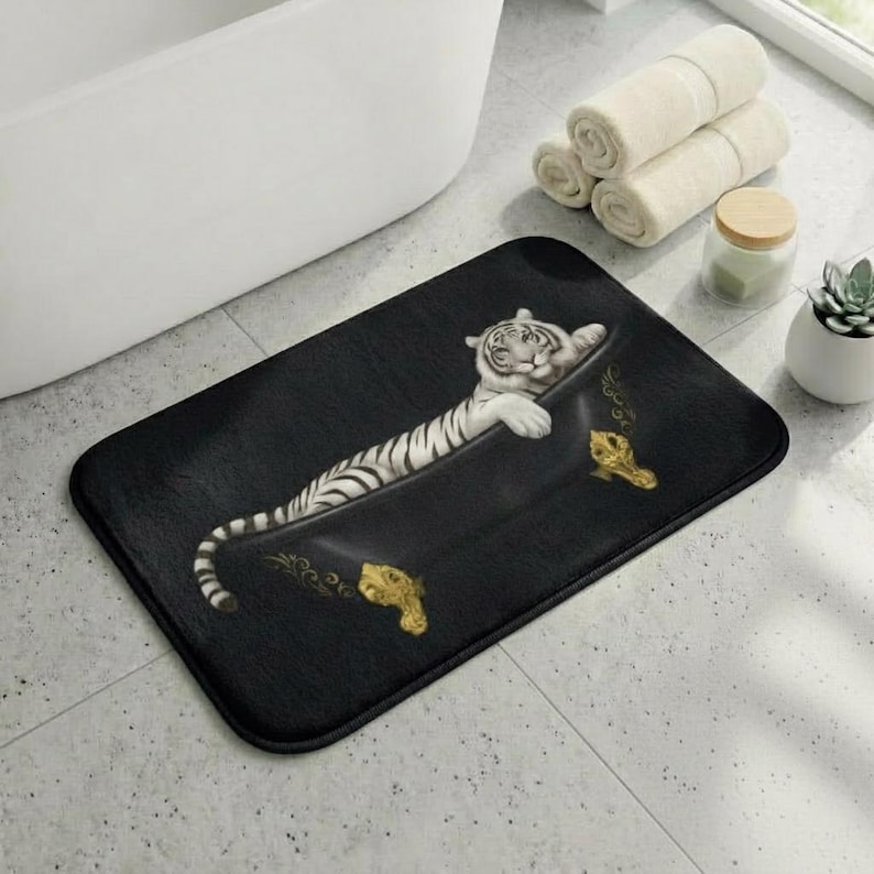 May include: Black rectangular bath mat featuring a white tiger relaxing in a black bathtub. The tiger has black stripes and is lying down. The bathtub has gold accents. The mat is on a tiled floor.