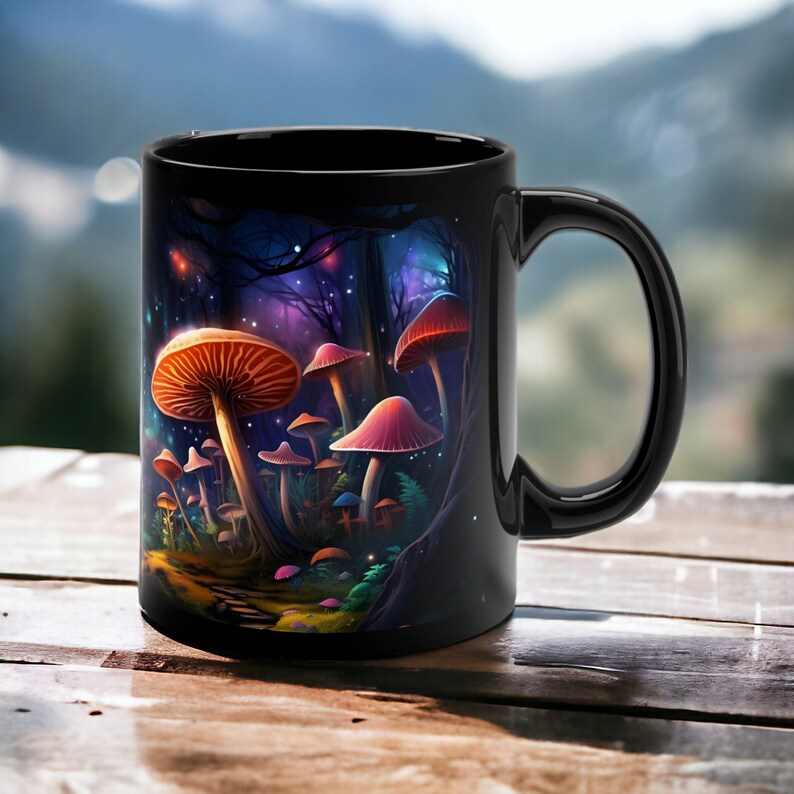 K&ouml;nnte beinhalten: Schwarze Keramiktasse mit einer farbenfrohen Illustration von Pilzen in einer Waldlandschaft. Die Pilze sind rot, orange und rosa mit wei&szlig;en Punkten. Der Hintergrund ist dunkelblau mit Sternen.