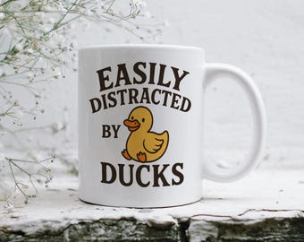 May include: White ceramic mug with a black and brown graphic that says "Easily Distracted by Ducks" and a cartoon image of a yellow duck.