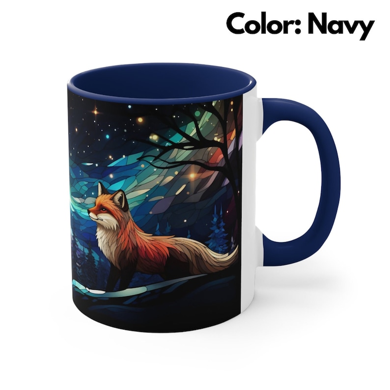 May include: A white ceramic mug with a navy blue rim and handle. The mug features a colourful stained glass style illustration of a fox standing in a forest at night with a starry sky. The text "Color: Navy" is visible in the top right corner of the image.