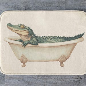 Op de afbeelding: Een groene alligator die een bad neemt in een wit porseleinen bad met sierlijke pootjes. Het bad staat op een crèmekleurige achtergrond.